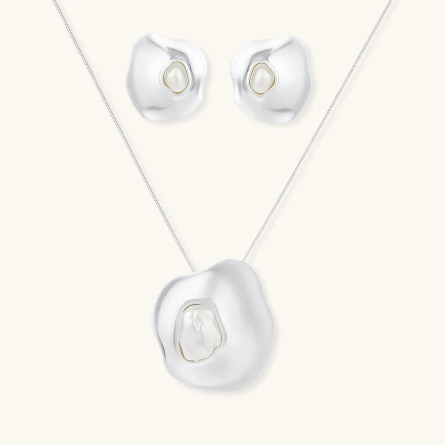 Organic curved earrings and necklace featuring baroque pearls in eco-zinc alloy settings on neutral background