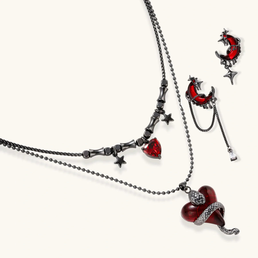 Gothic jewelry set with asymmetrical black metal earrings featuring red crescent moons, stars, and layered necklaces with heart pendants