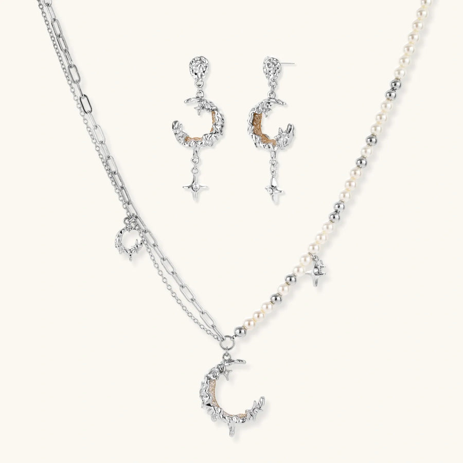 Mixed-metal jewelry set featuring layered necklaces with crescent moon pendant and pearl beads, plus matching star-drop earrings.