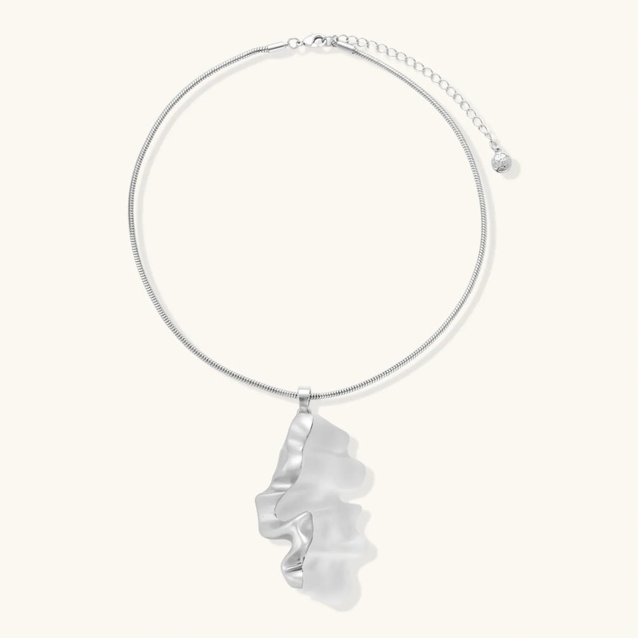 Modern sculptural pendant necklace with twisted metallic design on delicate silver chain against neutral background.