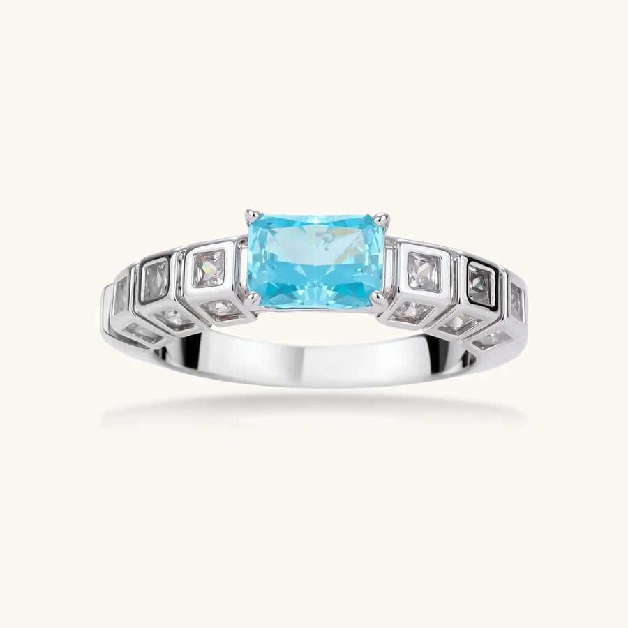 Geometric silver-plated ring with rectangular aqua cubic zirconia center and square crystal details on adjustable band.