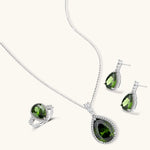 White gold plated jewelry set with green teardrop gemstones and cubic zirconia halos on cream background.