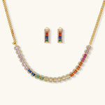 Gold-plated jewelry set featuring rainbow baguette-cut cubic zirconia stones in geometric design on cream background