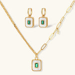 Gold-plated jewelry set with white enamel square pendants and emerald CZ stones on cream background.