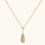 Gold-plated teardrop necklace and earrings covered in AAA cubic zirconia crystals on cream background.