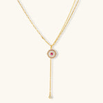 Gold-plated circular medallion necklace set with white enamel base and pink cubic zirconia accent stones