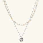 Two-layer necklace with natural stone chips and eco-brass beads, featuring a circular wrapped pendant on cream background.