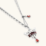 Silver-tone crown pendant with red zirconia stones and matching asymmetrical earrings on cream background
