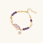 Gold-plated bracelet with baroque pearl centerpiece, amethyst beads, and crystal star charm on white background.