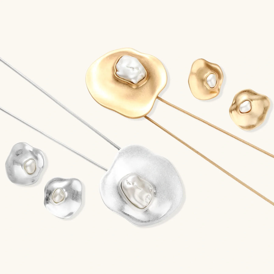 Organic curved earrings and necklace featuring baroque pearls in eco-zinc alloy settings on neutral background