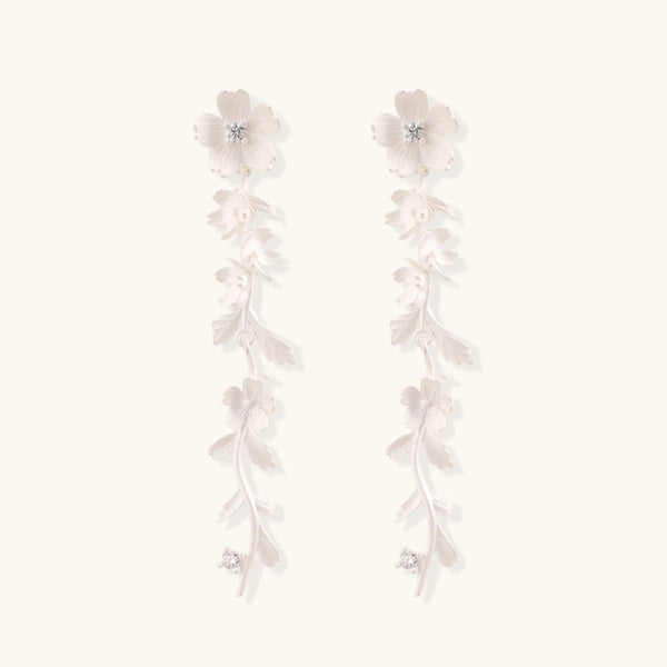 Long sterling silver drop earrings with delicate floral vine design and crystal accents on white background