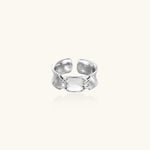 Adjustable silver-toned ring with sculptural stitch design across polished white gold-plated brass band