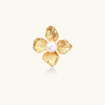 Gold-plated flower ring with textured petals and white cotton pearl center on cream background