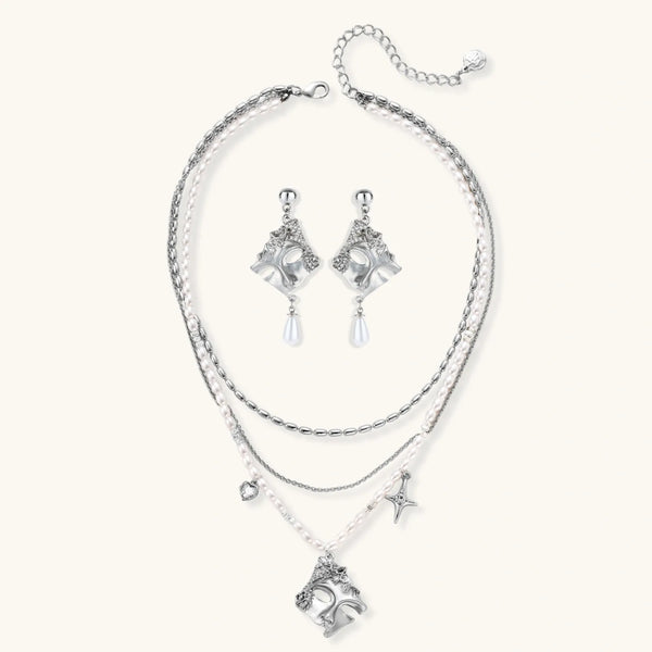 Ornate silver-toned masquerade mask jewelry set featuring rhinestone details and pearl drop earrings on white background.