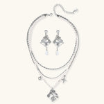 Ornate silver-toned masquerade mask jewelry set featuring rhinestone details and pearl drop earrings on white background.