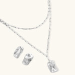 Modern textured hoop earrings and layered chain necklace with liquid metal pendant in silver and gold finishes.
