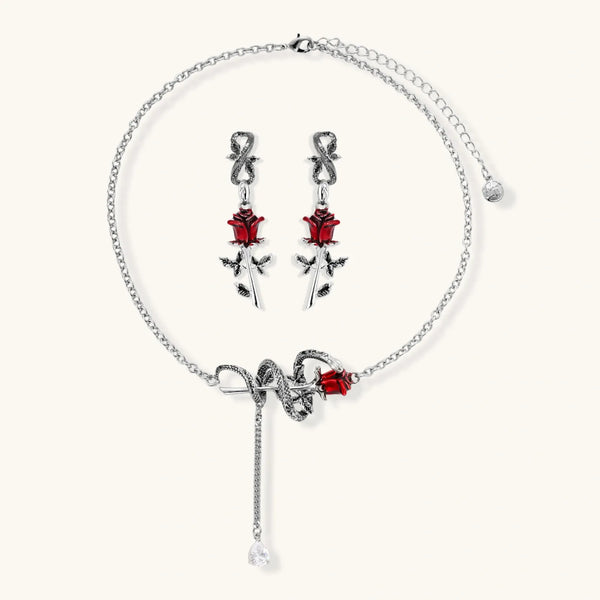 Gothic jewelry set with silver snake designs holding red enamel roses, featuring detailed leaf stems on cream background