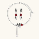 Gothic jewelry set with silver snake designs holding red enamel roses, featuring detailed leaf stems on cream background