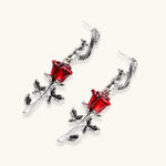 Gothic jewelry set with silver snake designs holding red enamel roses, featuring detailed leaf stems on cream background