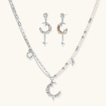 Mixed-metal jewelry set featuring layered necklaces with crescent moon pendant and pearl beads, plus matching star-drop earrings.