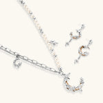 Mixed-metal jewelry set featuring layered necklaces with crescent moon pendant and pearl beads, plus matching star-drop earrings.