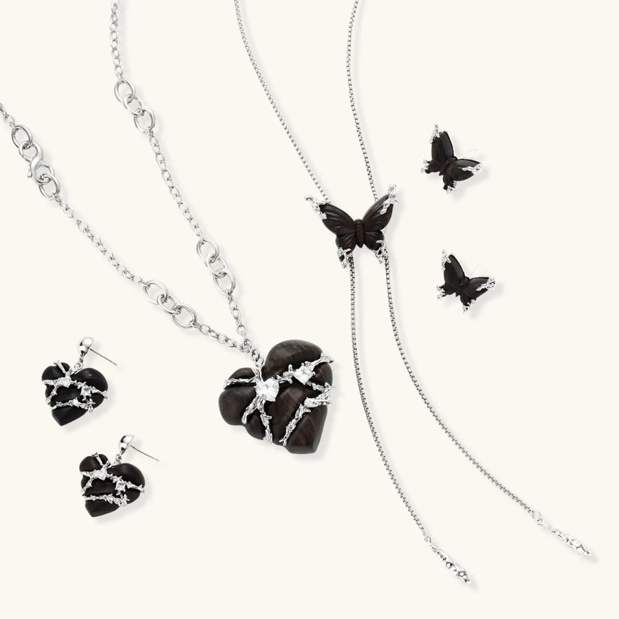 Dark wood butterfly earrings and necklace with silver chain accents on white background, showing natural grain texture.