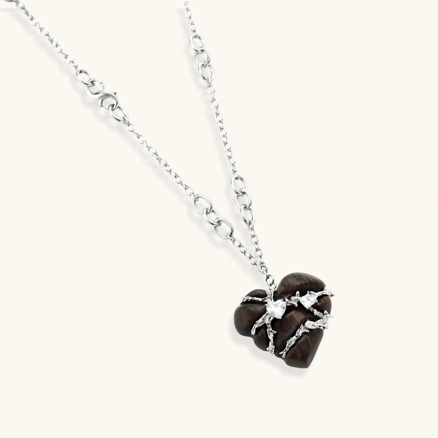 Dark ebony wood heart charms wrapped in intricate silver chains with crystal accents, shown as matching earrings and necklace set.