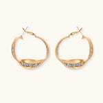 Sculptural wavy hoop earrings with crystal details and organic curved silhouette in gold and silver variants