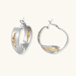 Artistic jewelry set featuring curved silver pendant with gold veining on black cord plus matching asymmetrical hoop earrings