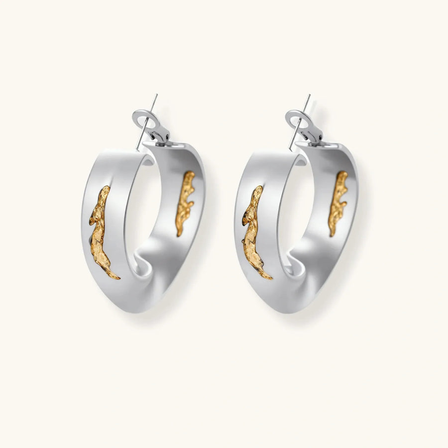 Artistic jewelry set featuring curved silver pendant with gold veining on black cord plus matching asymmetrical hoop earrings