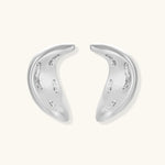 Curved crescent-shaped earrings in gold and silver with scattered perforated details on neutral background.