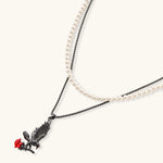 Dark gunmetal jewelry set featuring detailed raven pendants carrying red enamel roses with layered pearl and chain necklaces