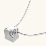 Close-up of a silver-toned molten cube pendant necklace with organic flowing texture on a minimalist chain