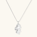 Modern sculptural pendant necklace with twisted metallic design on delicate silver chain against neutral background.