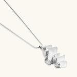 Modern sculptural pendant necklace with twisted metallic design on delicate silver chain against neutral background.