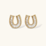 Gold-plated horseshoe necklace and earring set with baguette and round crystals arranged in geometric pattern on white background.