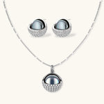 White gold plated spherical jewelry set with zirconia crystal pavé and dark lustrous centers on neutral background.
