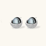 White gold plated spherical jewelry set with zirconia crystal pavé and dark lustrous centers on neutral background.