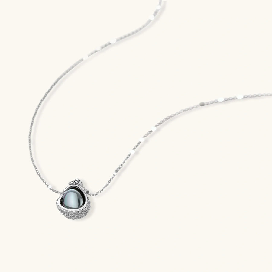 White gold plated spherical jewelry set with zirconia crystal pavé and dark lustrous centers on neutral background.