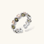 Adjustable copper ring with platinum plating, featuring alternating peach and green zirconia stones in organic wave pattern