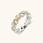 Close-up of an adjustable ring with golden zirconia stones in oval settings and clear accent stones on white gold-plated band.