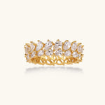 Adjustable gold-plated ring with double-row pear-shaped cubic zirconia stones in geometric pattern on cream background.