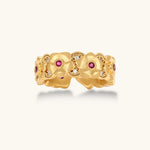 Adjustable gold-plated ring with burgundy zirconia centered flowers and crystal accents on cream background.