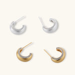 Close-up of small silver-plated hoop earrings with brushed texture and a row of sparkling zircon crystals on white background